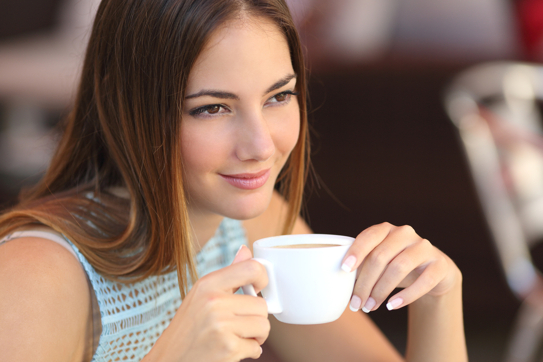 Candid woman thinking in a coffee shop holding a cup with an unfocused background